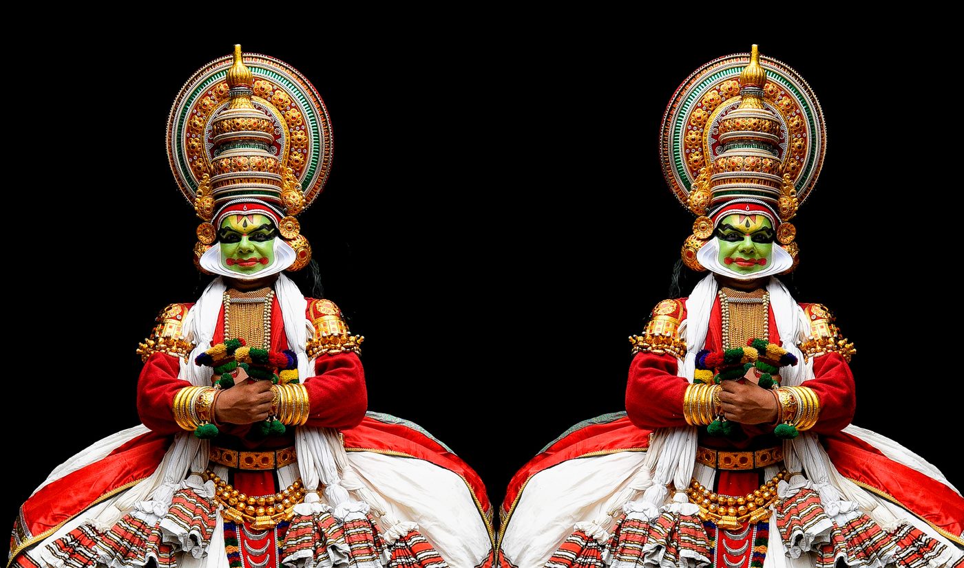 अँधेरे मंच पर पूर्ण वेशभूषा और हरी रूपसज्जा में कथकली कलाकार