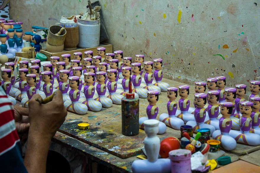 Artisan hand-painting rows of Channapatna wooden dolls in a workshop