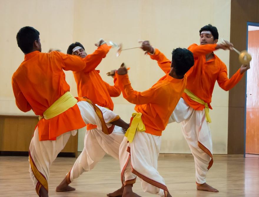 Kamsale dancers mid-performance, swinging bronze cymbals